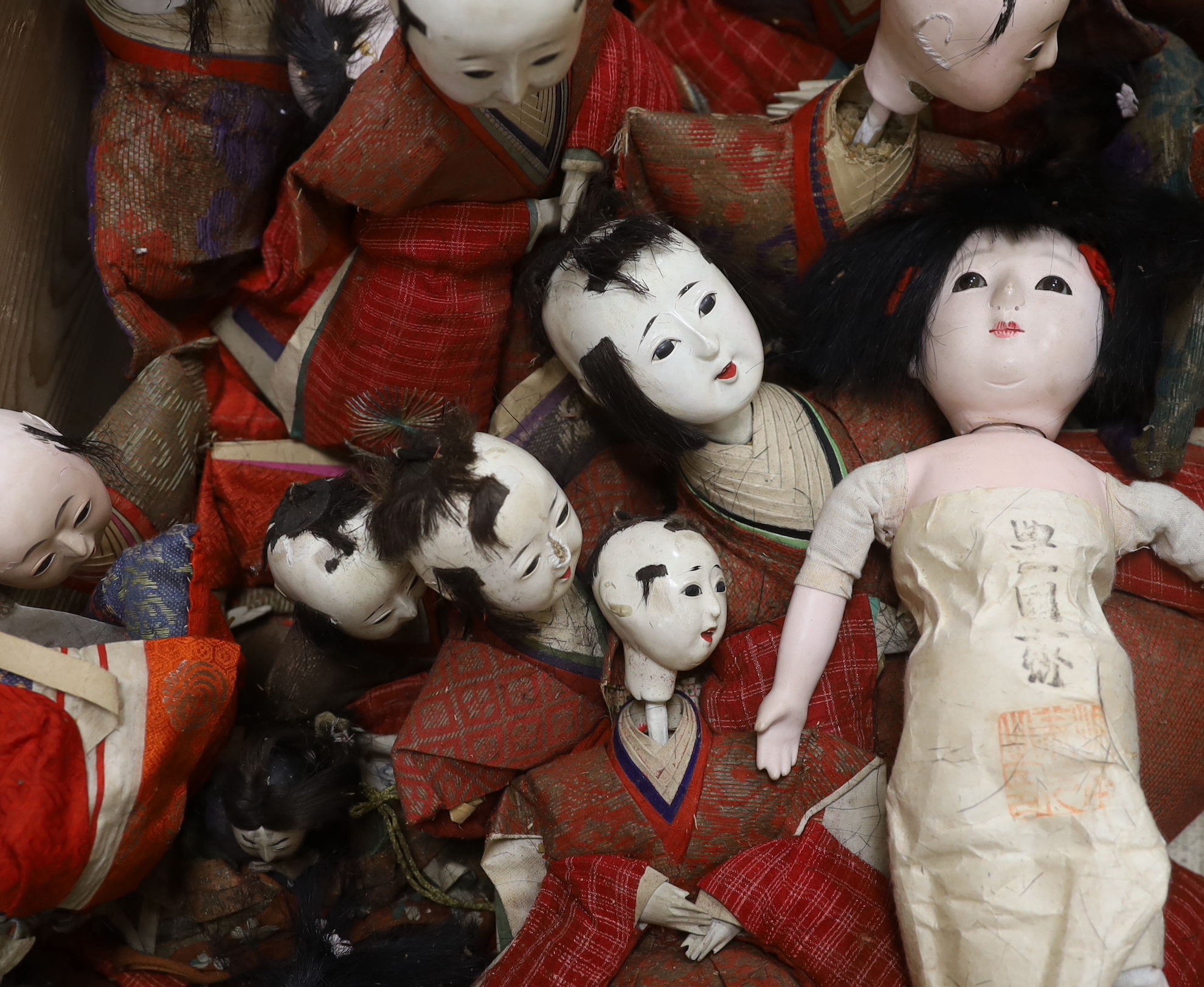 A collection of Japanese gofun dolls, some wearing kimonos, the largest 30cm high